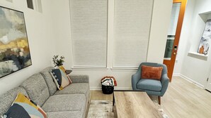 Un salon moderne avec un canapé gris, une table basse en bois et un tapis à motifs.