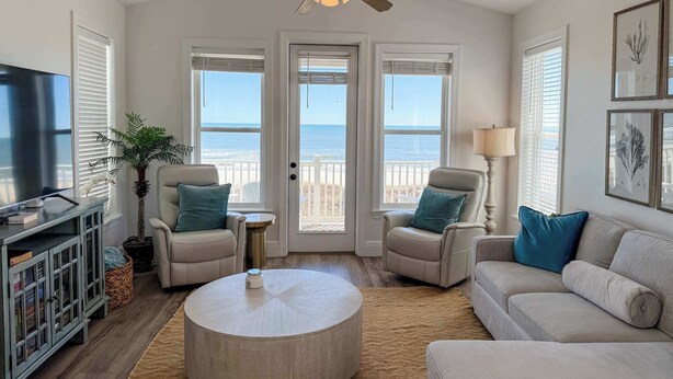 A living room with a TV, two chairs, a sofa, a round coffee table, and a ceiling fan. - Gulf-Front Paradise 3BR Beach House Prime Location (Saint George Island)