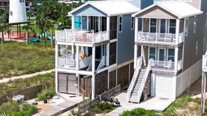 A beachfront property with a two-story building, a covered deck, and a staircase leading to the upper level. - Gulf-Front Paradise 3BR Beach House Prime Location (Saint George Island)