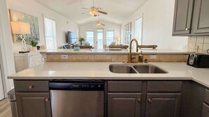 A modern kitchen with a dishwasher, double sink, and a ceiling fan. - Gulf-Front Paradise 3BR Beach House Prime Location (Saint George Island)