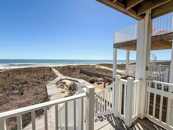 On peut admirer la plage depuis une terrasse en bois dotée de rampes blanches, un escalier en bois et un sentier sablonneux menant à la plage.