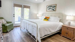 A bedroom with a bed, bedside table, and a green chair.