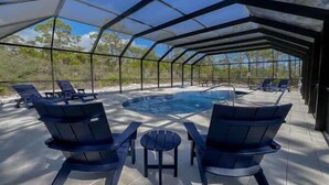 A covered outdoor area with a pool, lounge chairs, and a table.