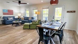 A spacious living area with a dining table, sofas, and a flag on the wall.
