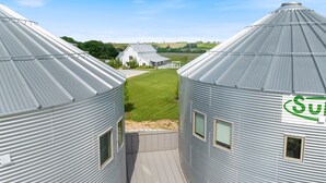 Uitzicht op twee grote metalen silo's, met een wit gebouw op de achtergrond.