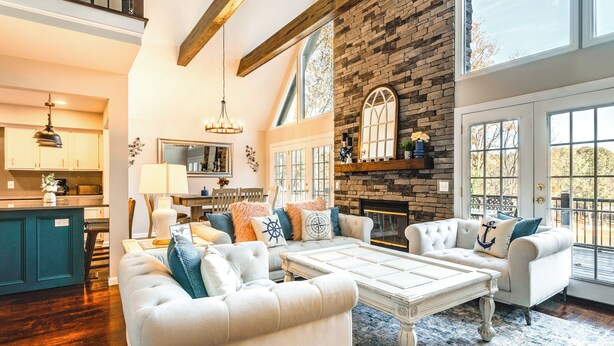 A spacious living area with a fireplace, a large window, and a kitchen in the background. - Dock & Hot Tub at High Rock Lake Retreat (Lexington)