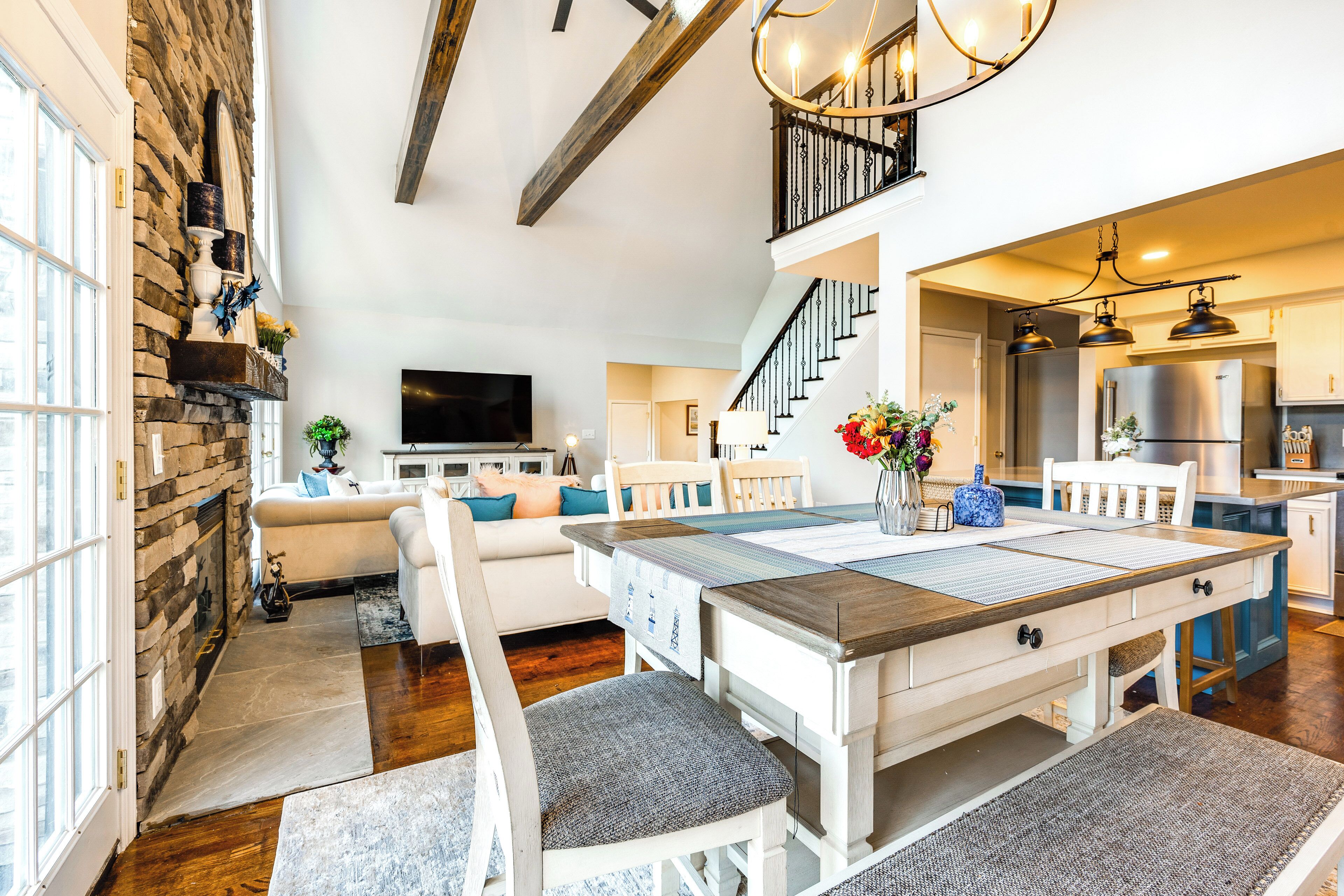 Un salon spacieux avec une cheminée, un coin repas avec une grande table et une cuisine équipée d’appareils modernes.