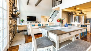 A spacious living room with a fireplace, a dining area with a large table, and a kitchen with modern appliances. - Dock & Hot Tub at High Rock Lake Retreat (Lexington)