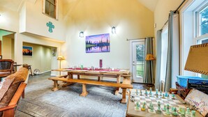 Une pièce spacieuse avec une grande table en bois, dressée pour le repas, un jeu d’échecs et un coin salon confortable avec un banc.