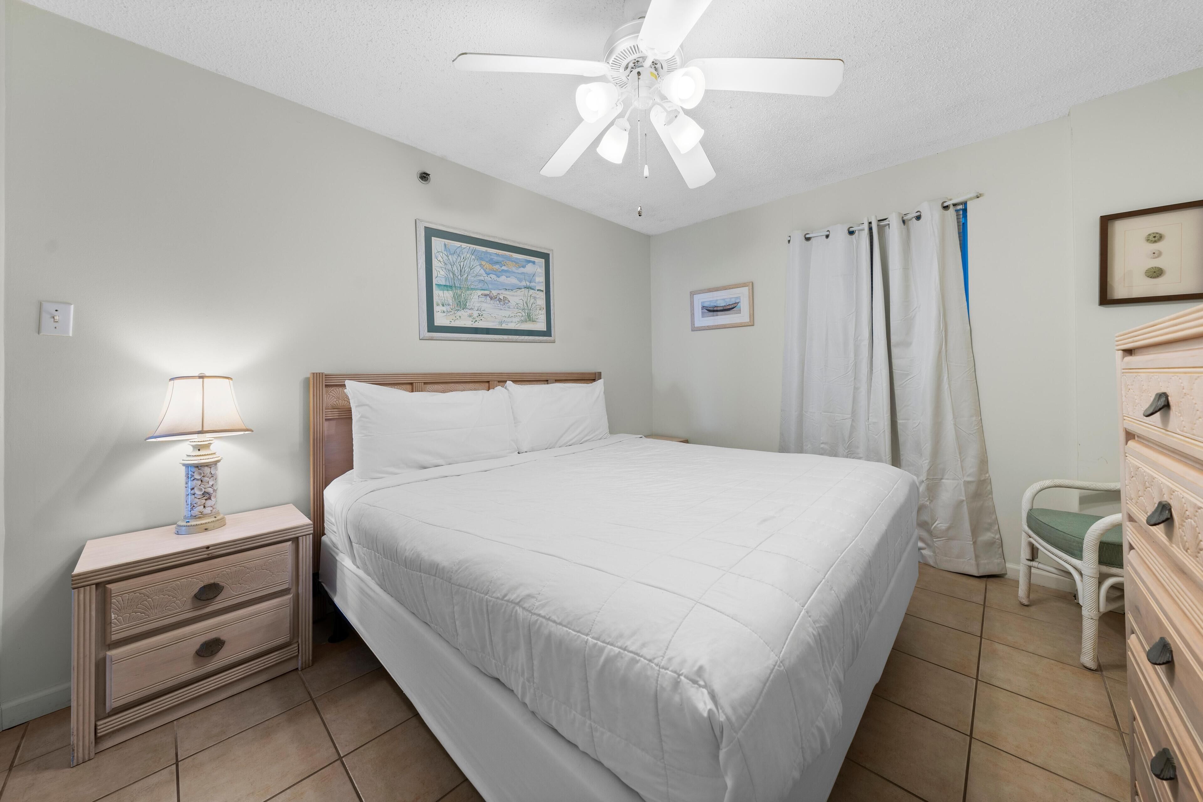 A bedroom with a bed, nightstand, dresser, and ceiling fan.