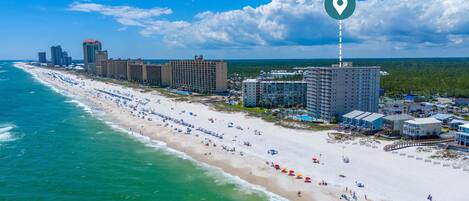 A coastal hotel with a beach view, multiple high-rise buildings, and a clear sky.