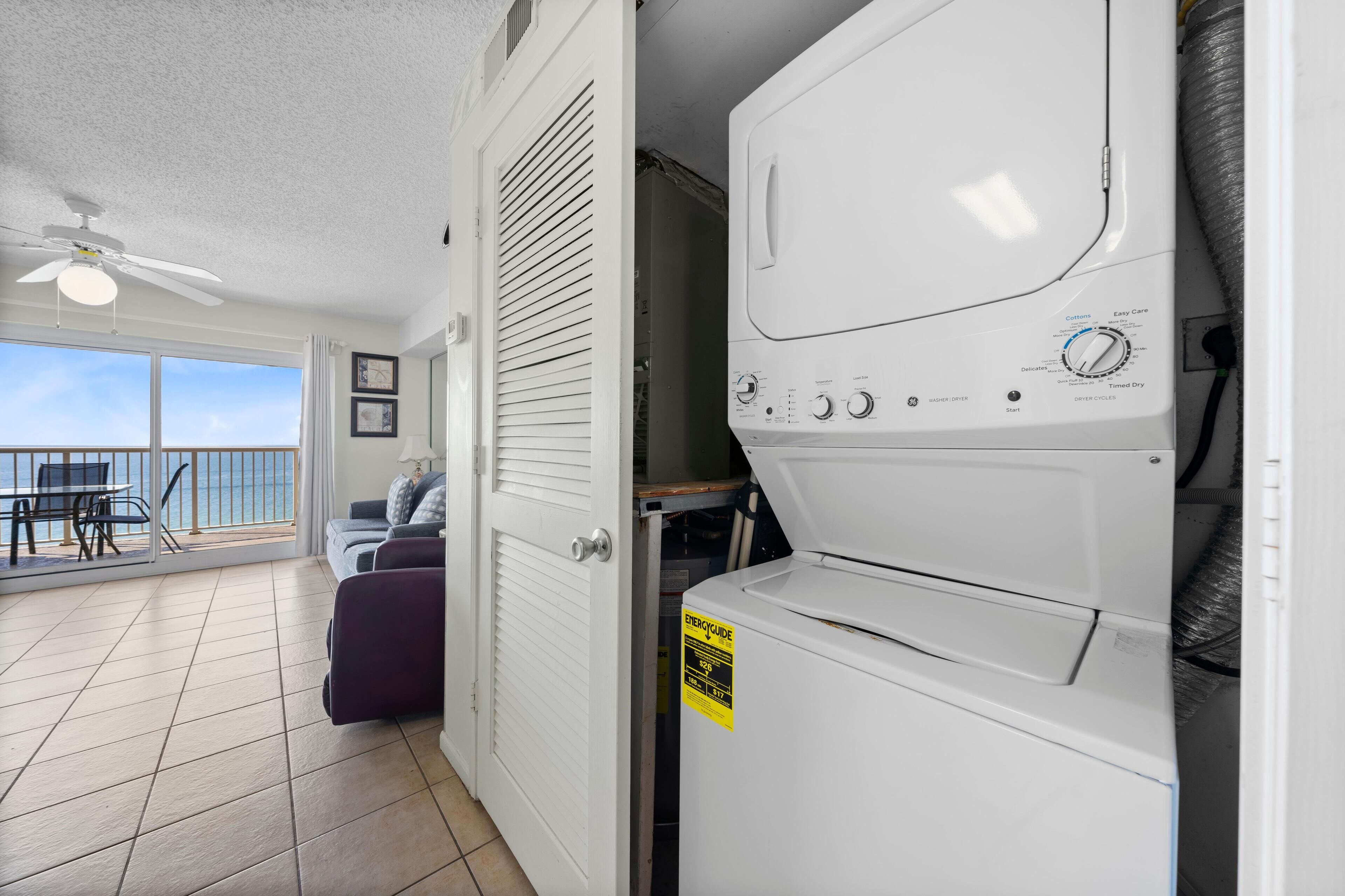 A laundry room with a washer and dryer, a ceiling fan, and a view of the balcony.