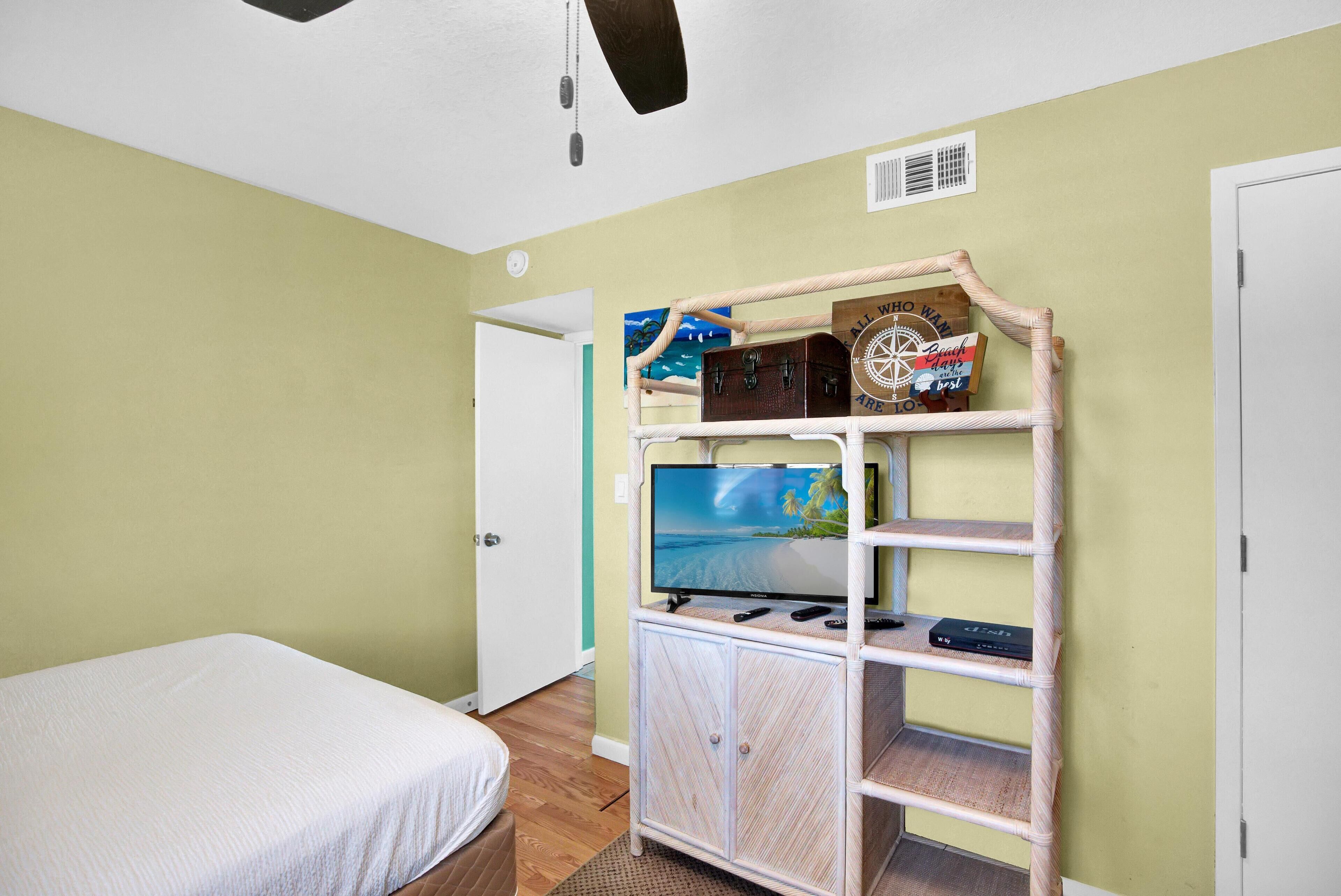 Una stanza con un letto, una TV su uno scaffale e una porta.