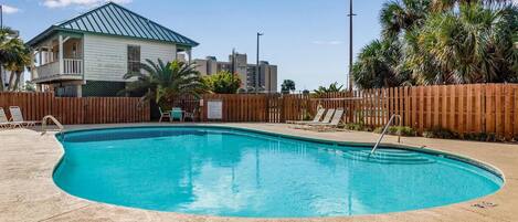 A swimming pool with lounge chairs and a wooden fence.