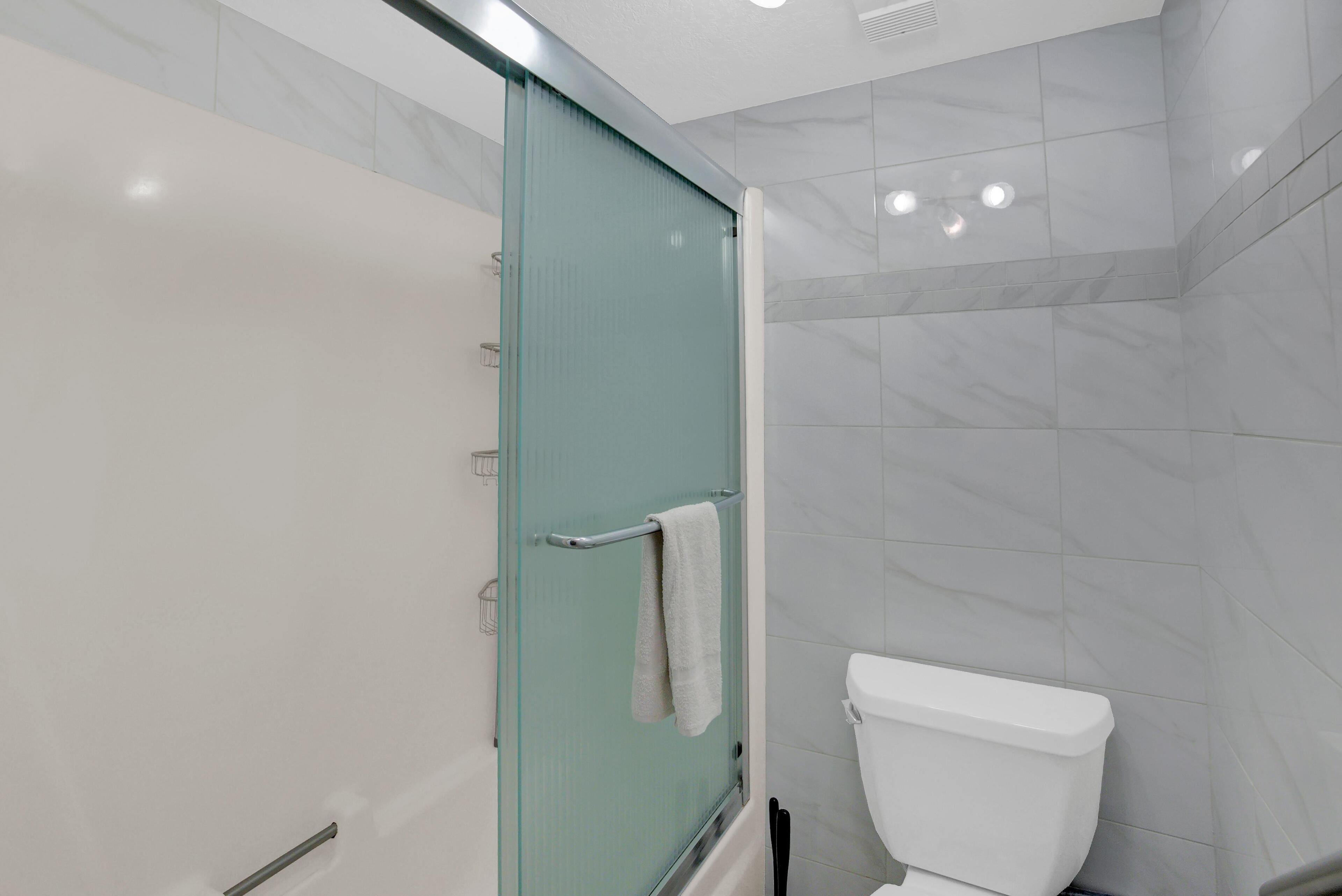 Ein modernes Badezimmer mit Duschkabine aus Glas, einer weißen Toilette und Marmorfliesen.