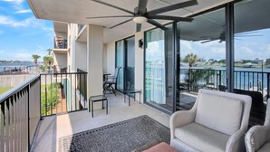 A balcony with a ceiling fan, a wicker sofa, a small table, and chairs. - Wind Drift 114n (Orange Beach)