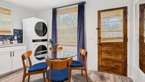 A compact kitchen with a washing machine, a dining table with chairs, and a wooden door. - Vibey 2-bedroom unit in duplex in Nashville (Madison)