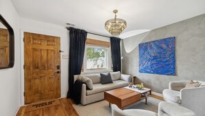 A modern living room with a wooden door, a sofa, a coffee table, and a large abstract painting on the wall. - Vibey 2-bedroom unit in duplex in Nashville (Madison)