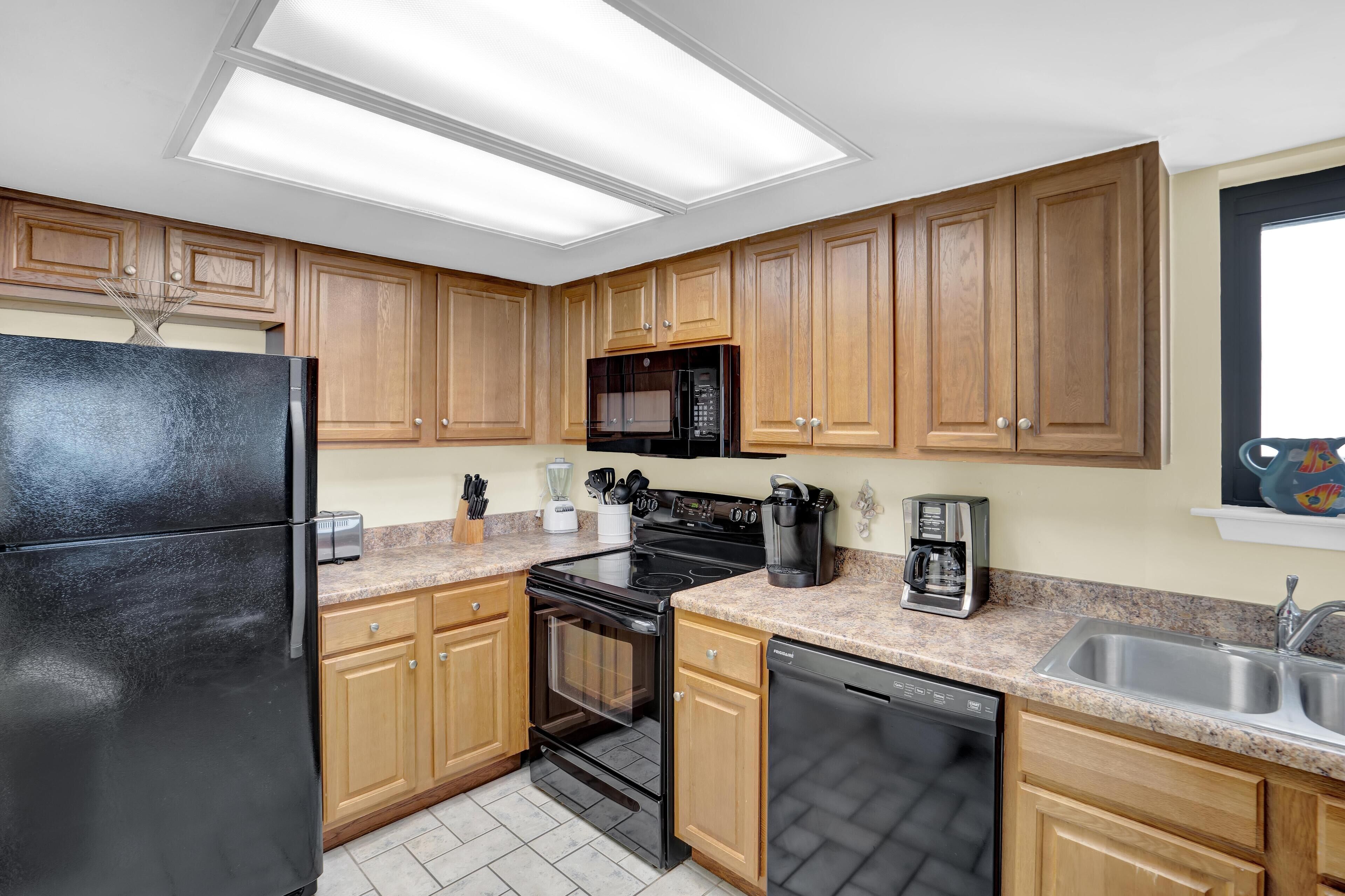 A kitchen with wooden cabinets, a black refrigerator, a microwave, a stove, and a dishwasher.
