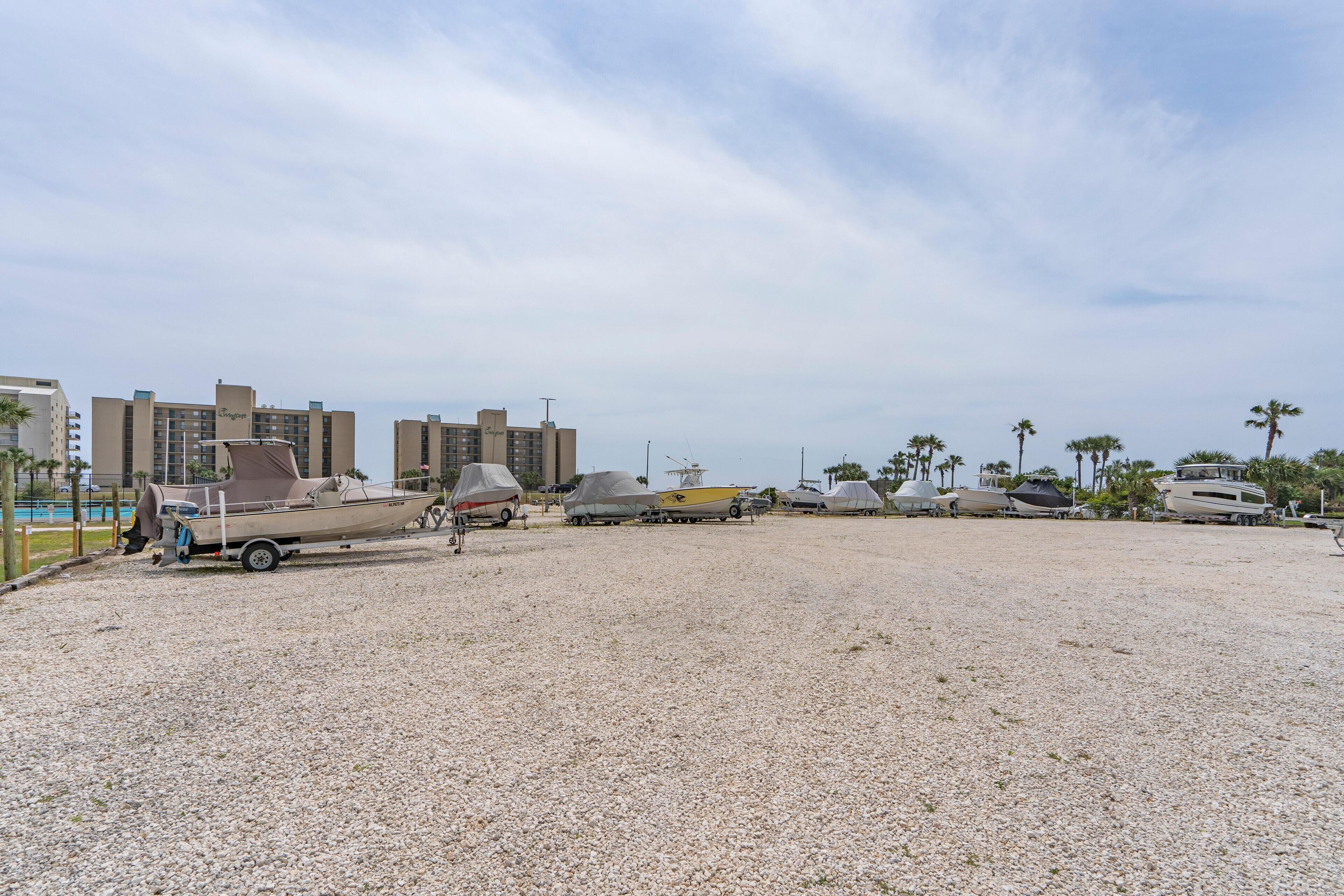 Un port de plaisance avec plusieurs bateaux recouverts de bâches, un bâtiment portant l’enseigne « Sofitel », et des palmiers en arrière-plan.