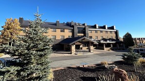 Un hotel de varios pisos con un diseño arquitectónico moderno, que cuenta con un patio central con una fuente de piedra y plantas en macetas.