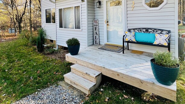 A two-story house with a porch, a welcome mat, and a bench. - Cozy 3-bedroom cottage with AC and WiFi in lovely Albrightsville (Albrightsville)