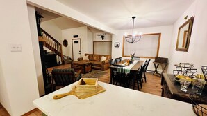 A spacious living room with a dining area, a staircase, and a kitchen visible in the background. - Cozy 3-bedroom cottage with AC and WiFi in lovely Albrightsville (Albrightsville)