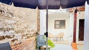 Un pequeño espacio al aire libre con una mesa, sillas y una gran sombrilla.