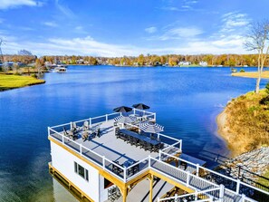 Un bateau amarré au bord de l’eau, doté de sièges extérieurs et d’une terrasse.