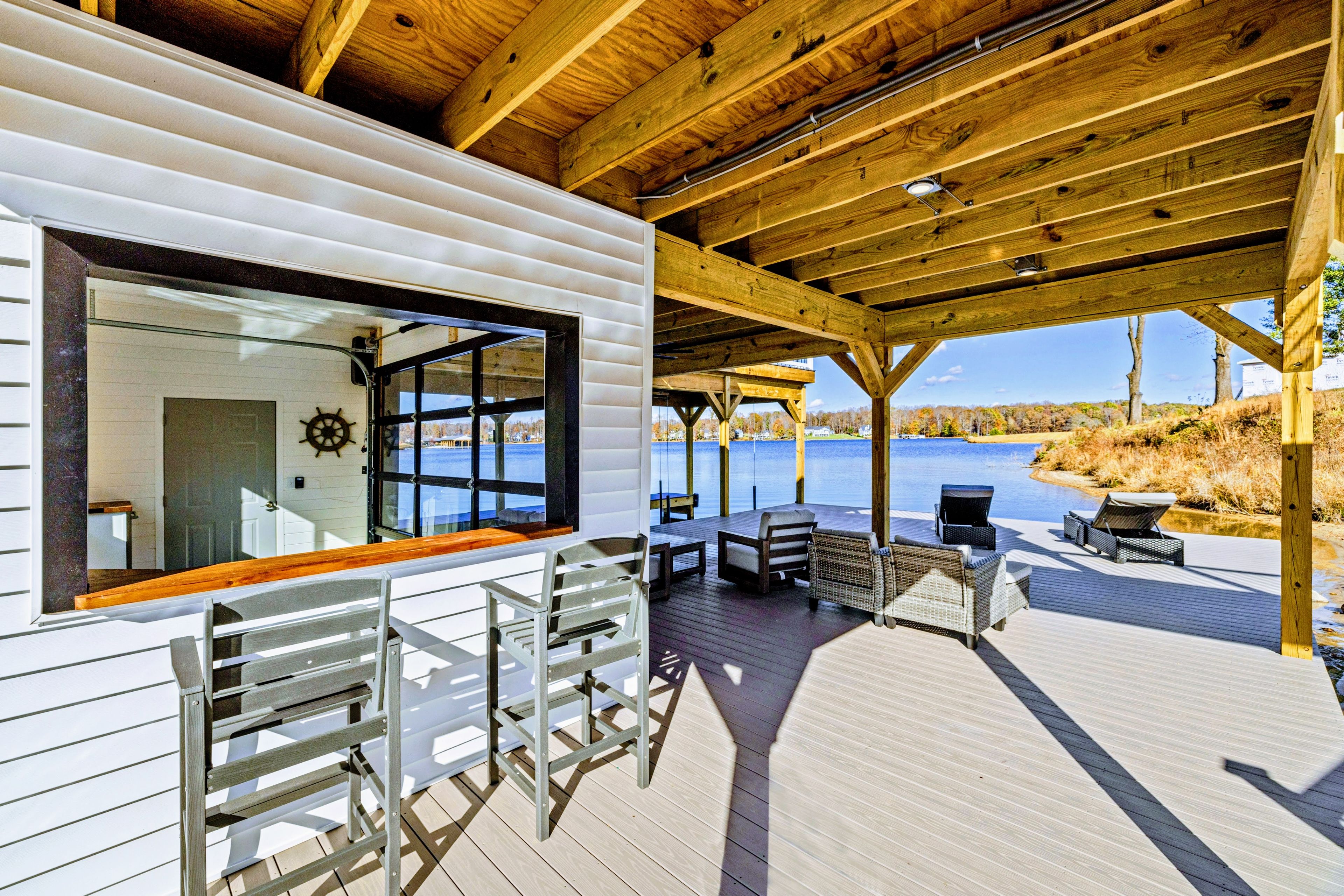 Une terrasse en bois avec des sièges extérieurs et une vue sur un lac.