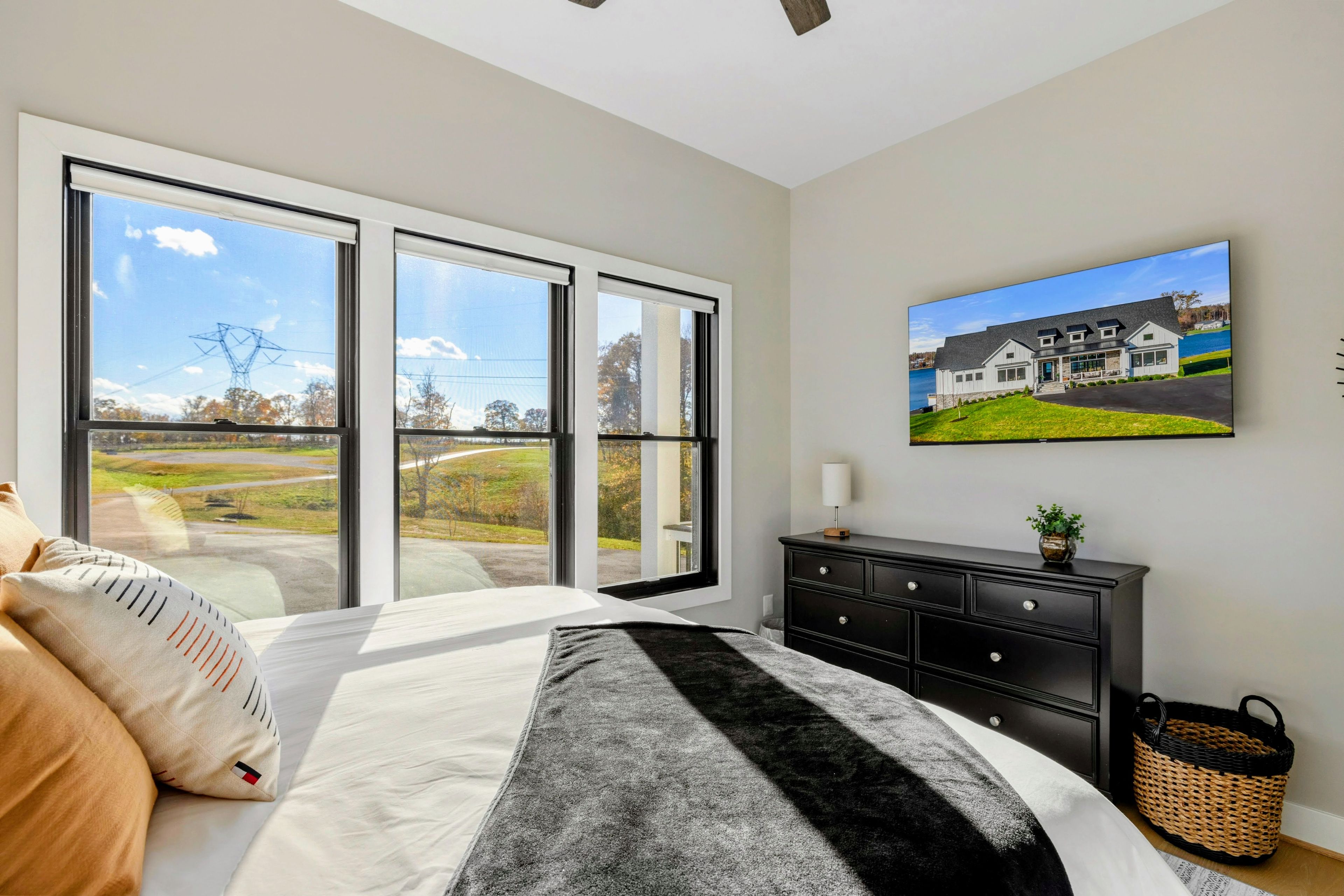 Une chambre à coucher avec un grand lit, une commode et un tableau représentant une maison.