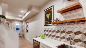 A modern kitchen with a stainless steel sink, wooden shelves, and a geometric backsplash. - Old Town Group Retreat - New to Brewery District! (Fort Collins)
