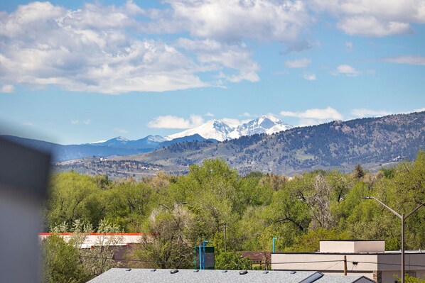 A view of a mountain range with snow-capped peaks, a clear sky, and a foreground of trees and buildings. - Old Town Group Retreat - New to Brewery District! (Fort Collins)