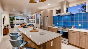 A modern kitchen with a central island, stainless steel appliances, and blue backsplash tiles. - Old Town Group Retreat - New to Brewery District! (Fort Collins)
