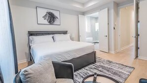 A modern bedroom with a large bed, a chair, a rug, and a framed picture on the wall. - Charming 3-Bedroom Luxury Home 5Min -> Downtown, NRG and Medical Center. (Houston)
