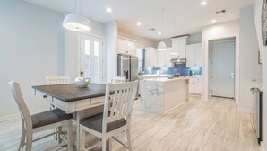 A modern kitchen with white cabinets, a marble island, and pendant lighting. - Charming 3-Bedroom Luxury Home 5Min -> Downtown, NRG and Medical Center. (Houston)