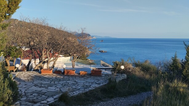 A coastal property with stone pathways, potted plants, and a view of the sea. - Cliff House with beautiful sea view. Panoramic views just infront of our terrace (Krstac)
