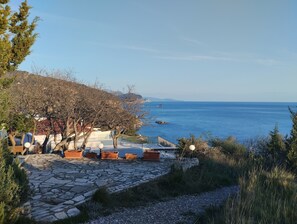 A coastal property with stone pathways, potted plants, and a view of the sea.