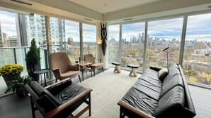 A modern living room with a city view, featuring a sofa, chairs, and a coffee table. - Beautiful Light-filled Apartment with Spectacular Views of Toronto (Toronto)