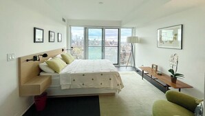 A modern bedroom with a large bed, a desk, and a view of the city. - Beautiful Light-filled Apartment with Spectacular Views of Toronto (Toronto)