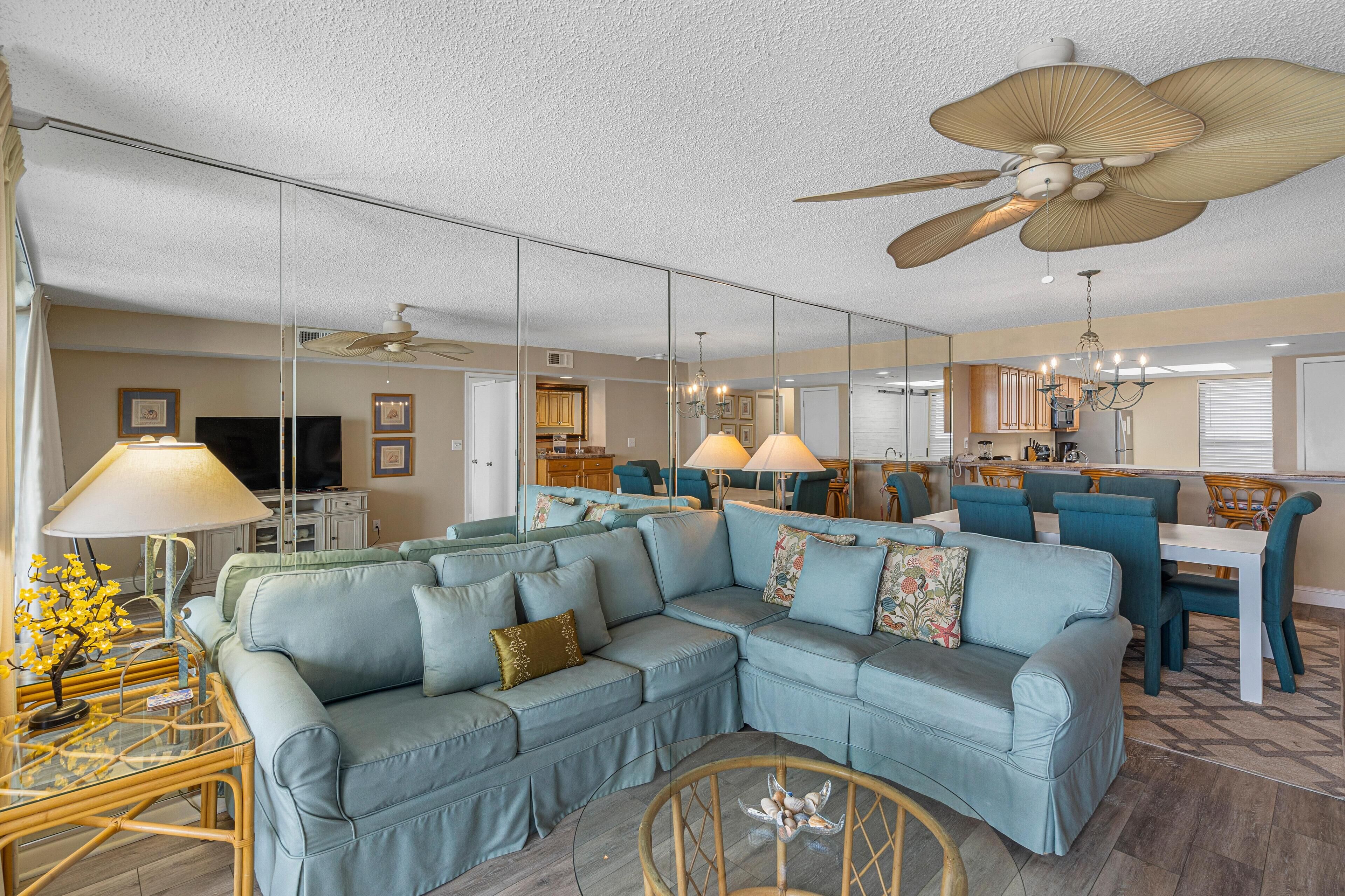 A spacious living room with a sectional sofa, a dining area, and a kitchen in the background.