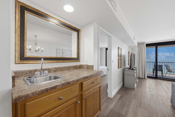 A modern kitchen with granite countertops, a double sink, and wooden cabinets. - Wind Drift 702e (Orange Beach)