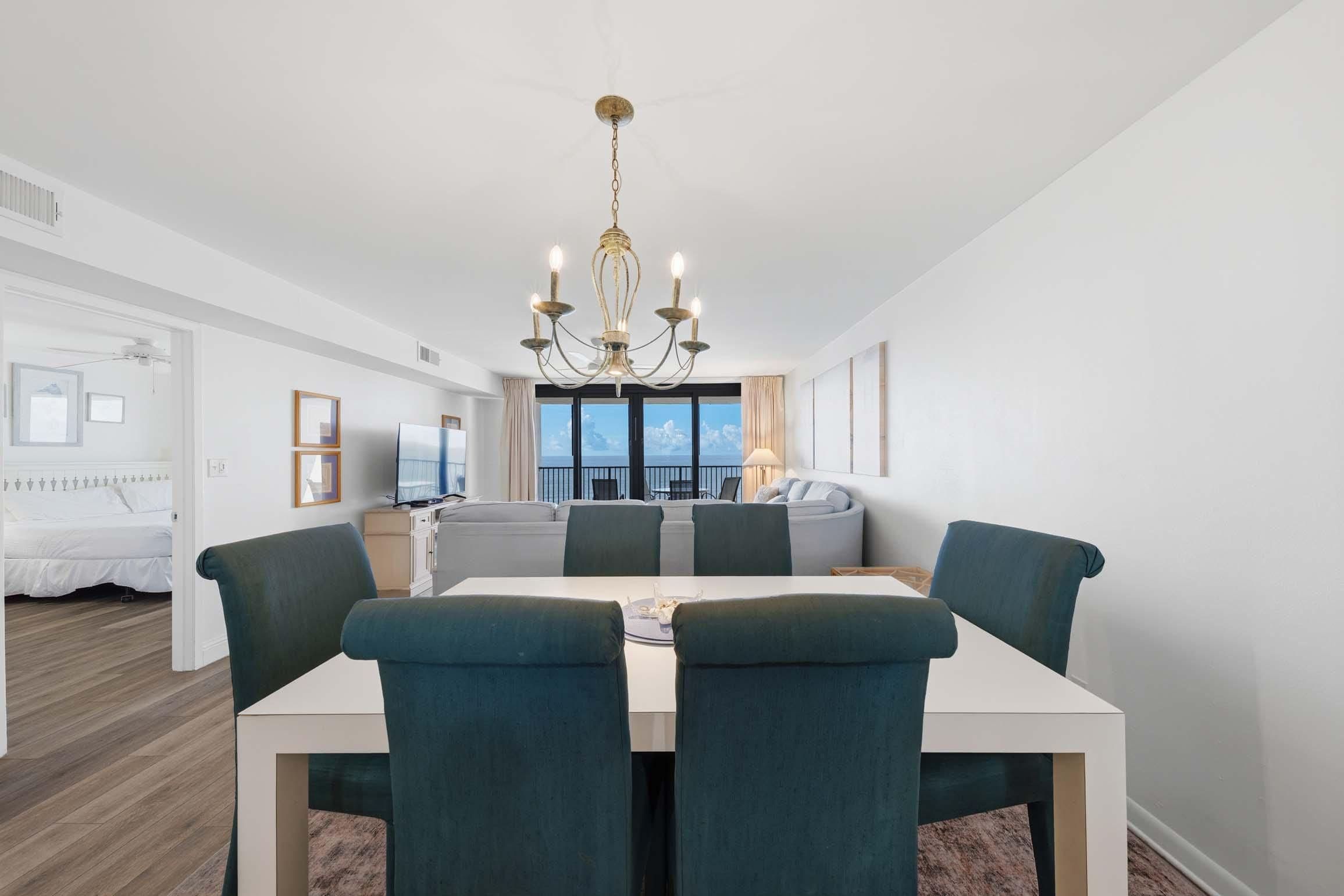 A modern dining area with a chandelier, a sofa set, and a view of the outdoors.