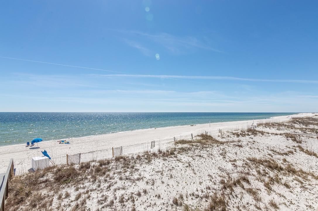 A beach with a sandy shore, a clear blue sky, and a calm sea.