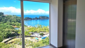 Ein Zimmer mit großem Fenster und Blick auf eine Küstenlandschaft, inklusive Aufzug und Wandbedienfeld.