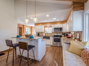 A modern kitchen with a central island, wooden accents, and a cozy seating area with a sofa and cushions. - The Cabin: Private Pool, Luxury Log Home (Grand Junction)
