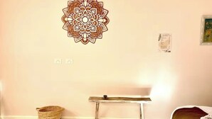 A bedroom with a bed, a wooden bench, a woven basket, a wall decoration, and a small framed picture. - Adorable 1br apt walking distance to Mullumbimby (Mullumbimby)