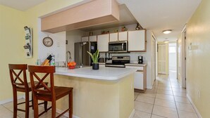 Une cuisine moderne dotée d’un îlot central, d’appareils électroménagers en acier inoxydable et de chaises en bois.