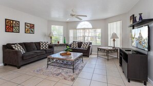 A living room with a sofa, coffee table, TV, and decorative items. - Villas at Island Club Community, pools, jacuzzi and more! (Kissimmee)