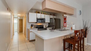 A modern kitchen with white cabinets, a stainless steel refrigerator, a microwave, and a sink. - Villas at Island Club Community, pools, jacuzzi and more! (Kissimmee)